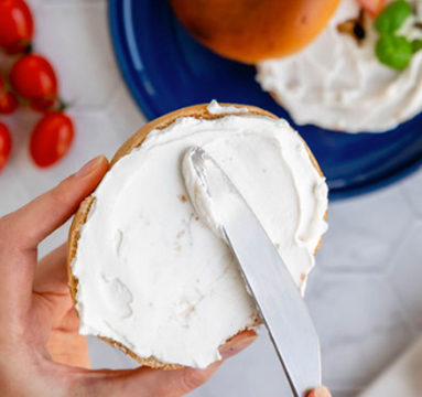 Cream cheese being spread on a bagel