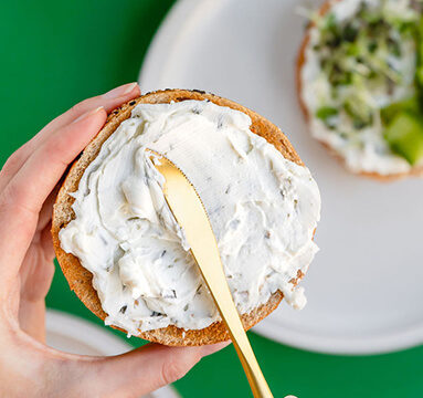 Chive & Onion Cream Cheese being spread on a bagel